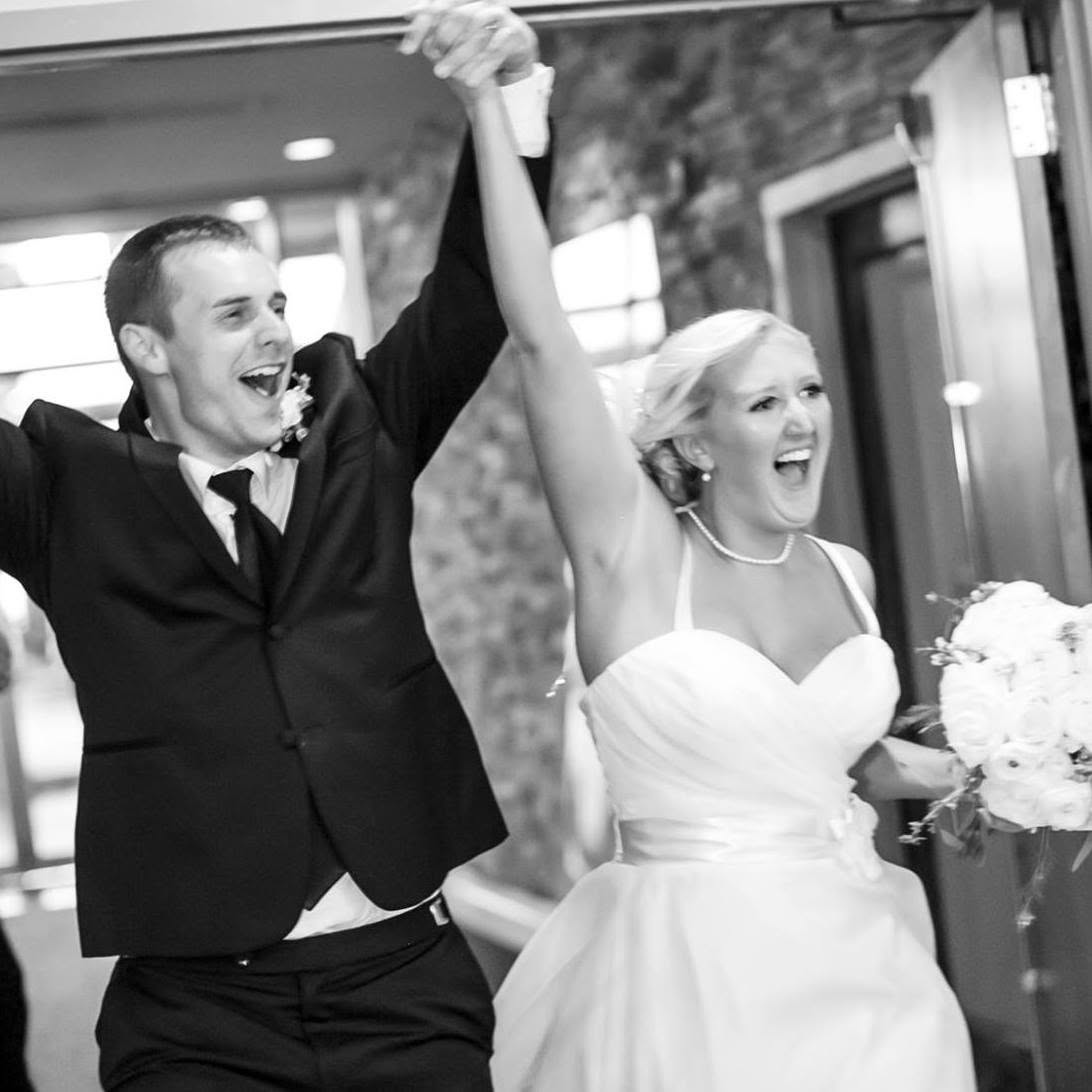 Melanie and her groom making a grand entrance at their wedding, hands clasped and raised