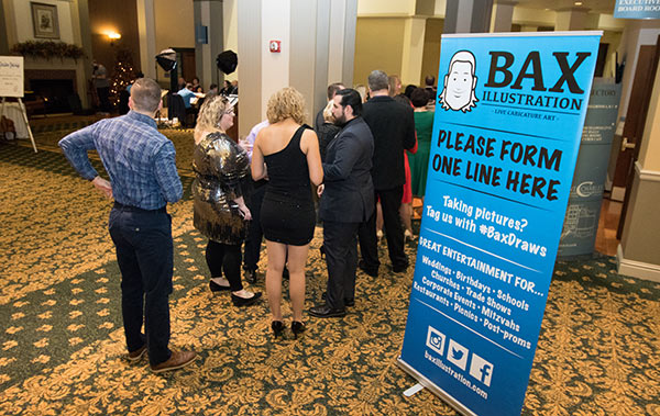 Wedding guests gather beside the Bax Illustration drawing station during cocktail hour