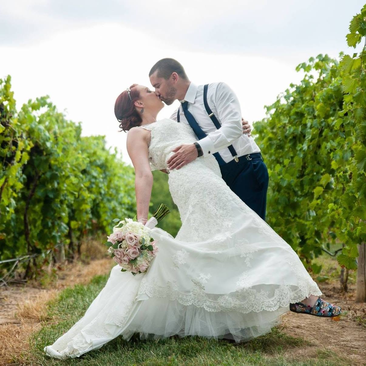 Stacie and her husband sharing a kiss at their vineyard wedding