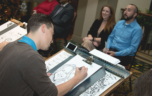 An artist draws a couple while family watches at a rehearsal dinner